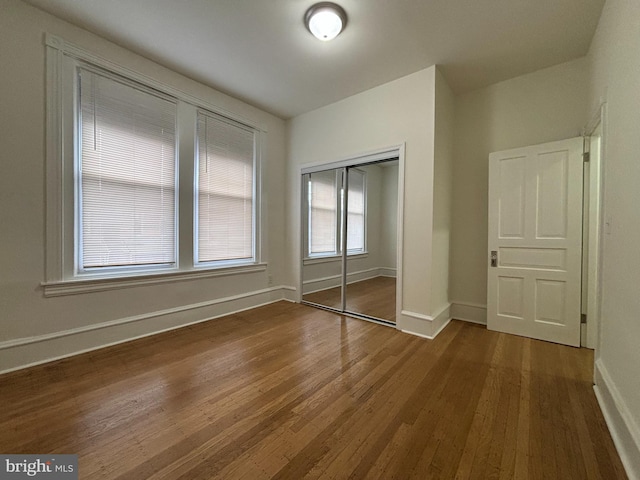 unfurnished bedroom featuring dark wood-type flooring, a closet, and baseboards