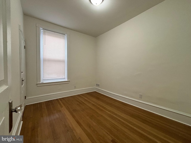 unfurnished room featuring visible vents, dark wood finished floors, and baseboards