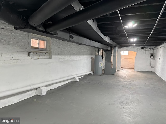 basement with water heater, visible vents, and heating unit