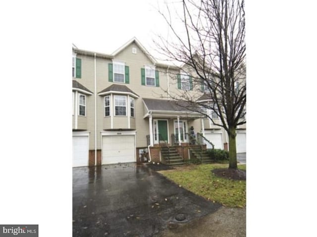 view of front of house with a porch, driveway, and a garage