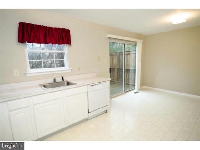 kitchen with a healthy amount of sunlight, white dishwasher, white cabinets, and a sink