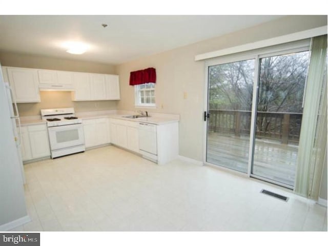 kitchen with white appliances, a sink, visible vents, white cabinets, and light countertops