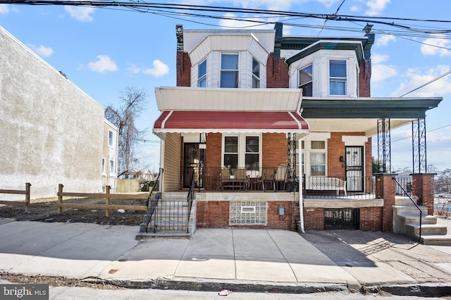 view of front of home featuring a fenced front yard, a porch, and brick siding