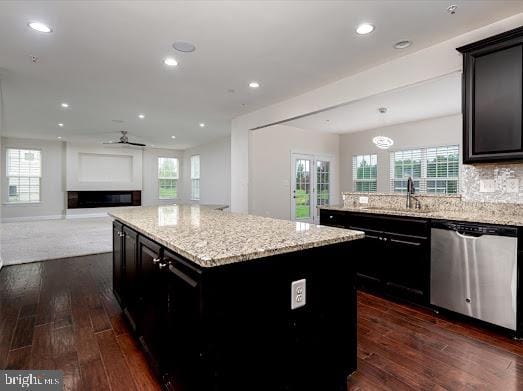 kitchen with dishwasher, dark wood-style flooring, a sink, and dark cabinets