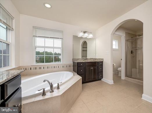 full bathroom featuring toilet, vanity, a shower stall, tile patterned flooring, and a bath