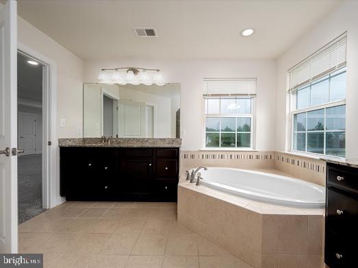 full bath with visible vents, a garden tub, vanity, and tile patterned floors