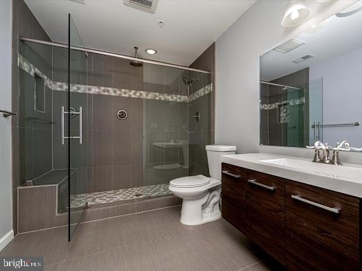 full bath with visible vents, a stall shower, vanity, and toilet