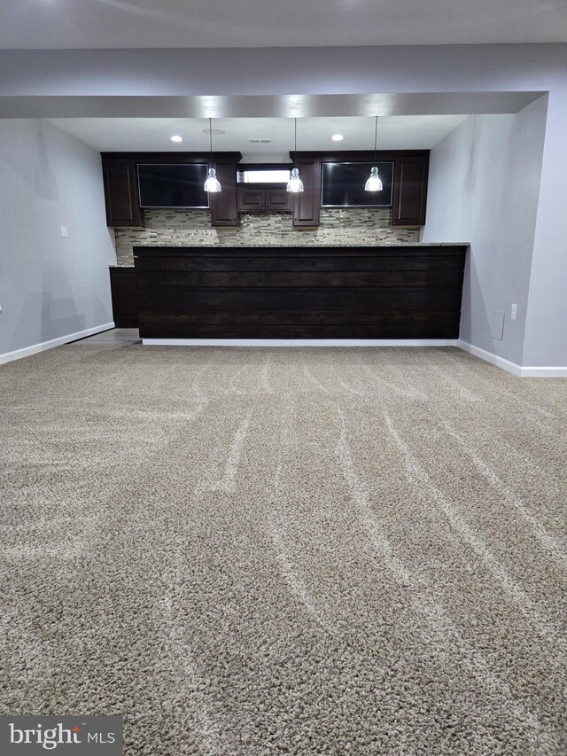 interior space featuring hanging light fixtures, dark brown cabinetry, baseboards, and backsplash