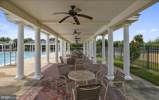 view of patio featuring outdoor dining area, fence, a community pool, and ceiling fan