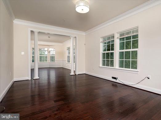 unfurnished room with baseboards, crown molding, ornate columns, and wood finished floors