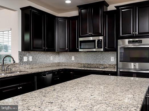 kitchen with black appliances, dark cabinetry, and a sink