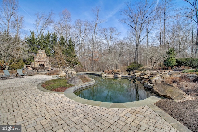 view of pool with an outdoor stone fireplace and a patio area