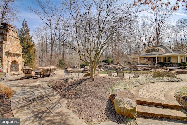 view of yard with an outdoor stone fireplace and a patio