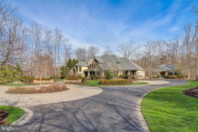 french country inspired facade with driveway, a front lawn, and stone siding