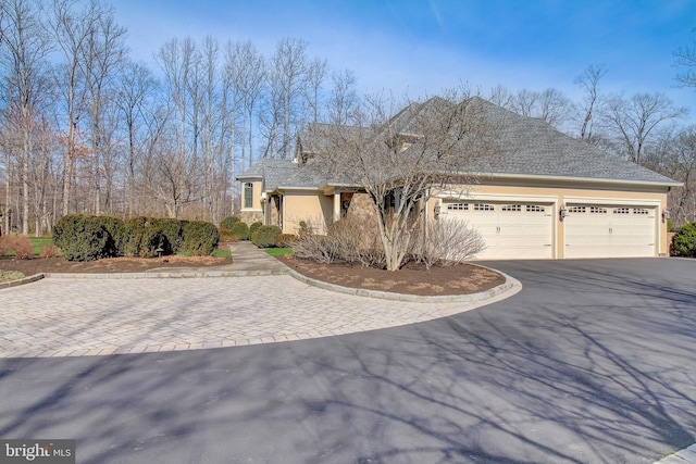 view of front of property featuring a garage, stone siding, aphalt driveway, and stucco siding