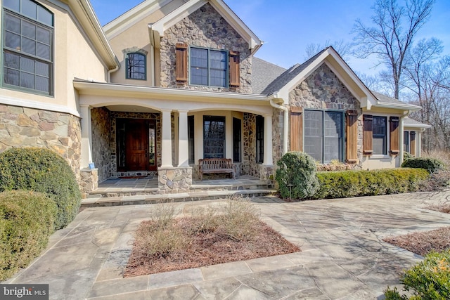 property entrance with stone siding and a porch