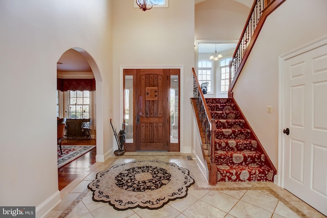 foyer entrance with stairway, a high ceiling, baseboards, and a chandelier