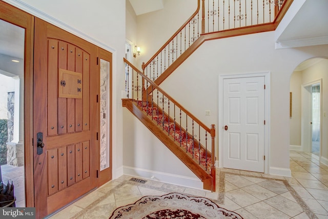 entryway featuring a towering ceiling, baseboards, and arched walkways