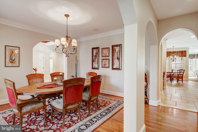 dining room featuring a chandelier, ornamental molding, baseboards, and light wood-style floors