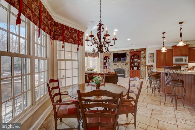 dining space featuring baseboards, a stone fireplace, stone tile flooring, and crown molding