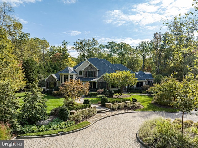 shingle-style home with driveway and a front lawn