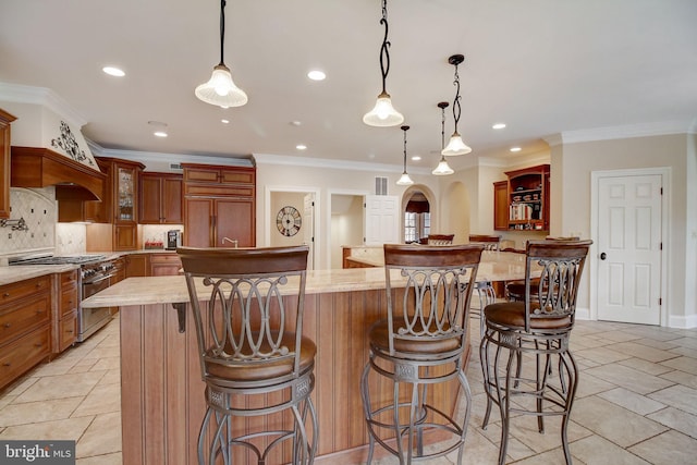 kitchen with arched walkways, premium appliances, a large island, backsplash, and brown cabinets