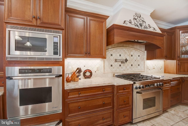 kitchen with light stone counters, brown cabinets, crown molding, decorative backsplash, and appliances with stainless steel finishes