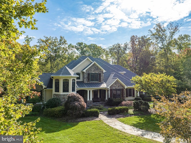 view of front of property featuring stone siding, metal roof, a front lawn, and a standing seam roof