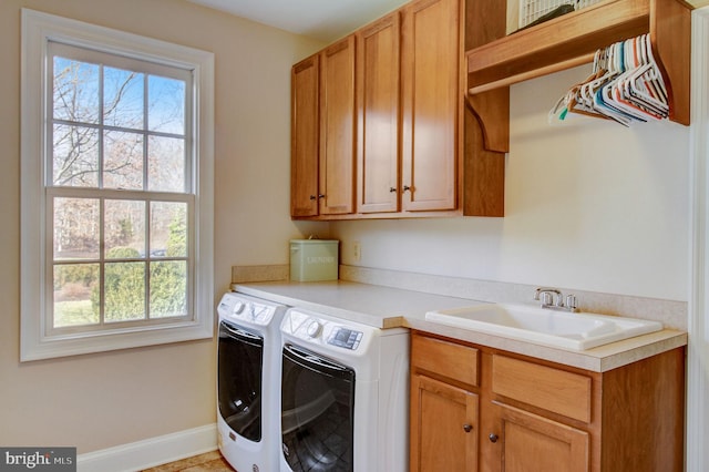 washroom with cabinet space, baseboards, a sink, and washing machine and clothes dryer