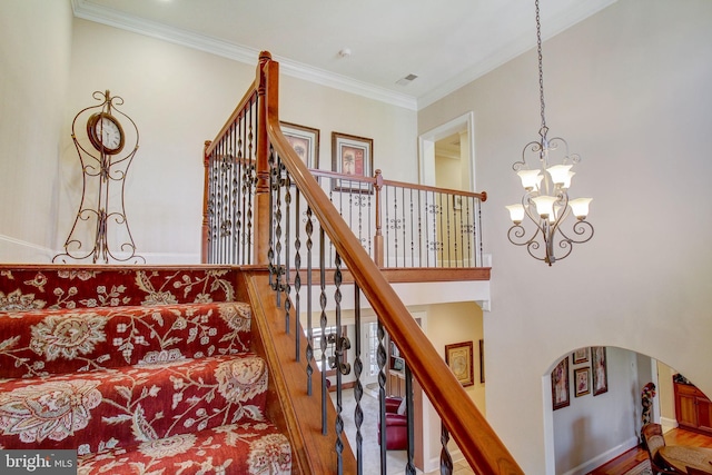 stairs with visible vents, arched walkways, ornamental molding, wood finished floors, and a chandelier