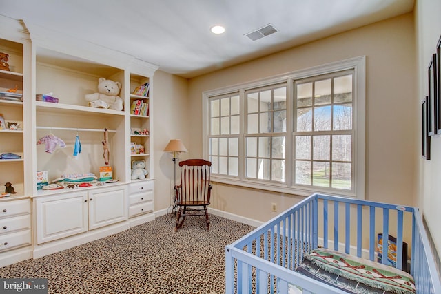 carpeted bedroom with a crib, recessed lighting, visible vents, and baseboards