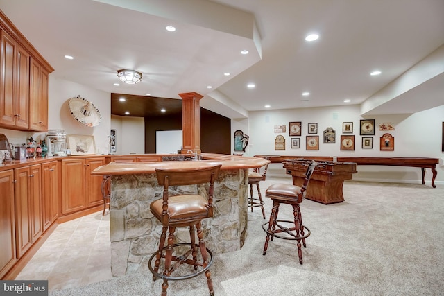 bar with light tile patterned floors, light colored carpet, recessed lighting, indoor wet bar, and decorative columns