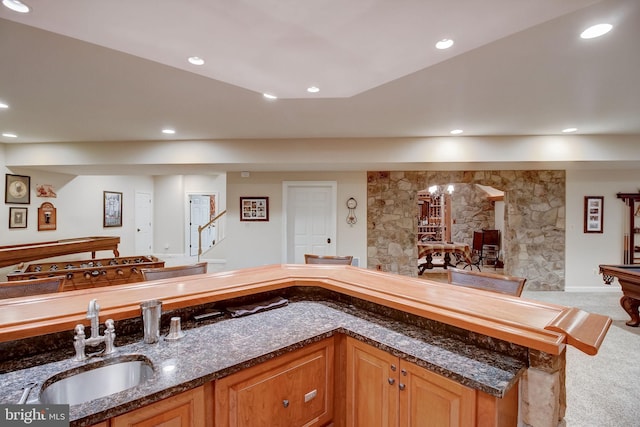 kitchen featuring carpet floors, recessed lighting, a sink, and dark stone countertops