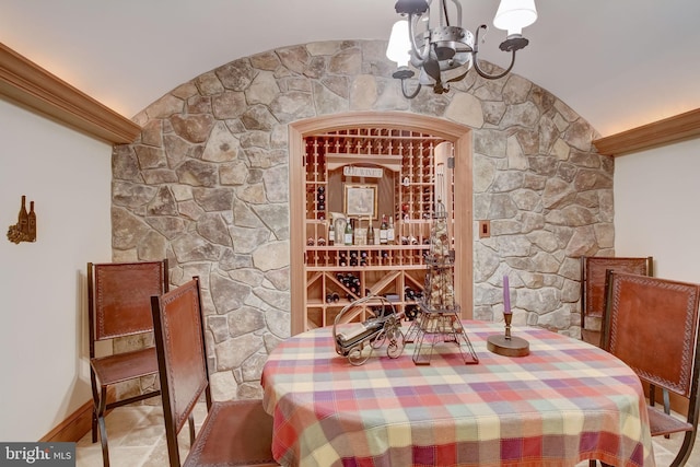 wine area with lofted ceiling, an inviting chandelier, and baseboards