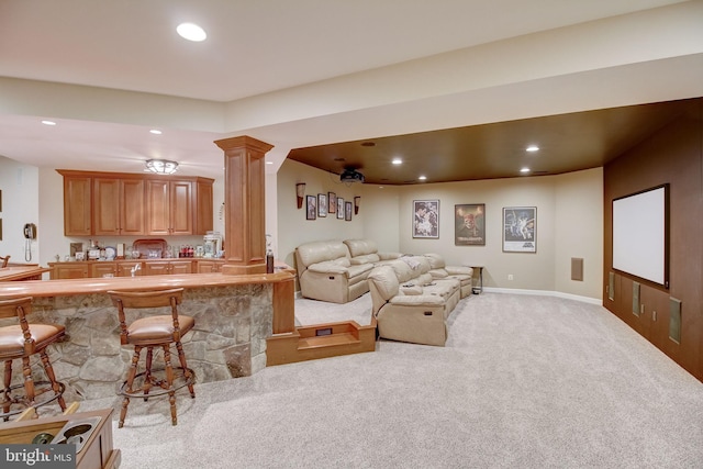 living area with light carpet, decorative columns, baseboards, wet bar, and recessed lighting