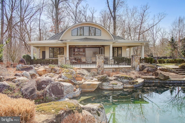 exterior space featuring a small pond and stucco siding