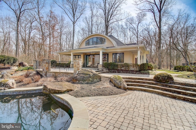 view of front facade with a pool, covered porch, fence, and stucco siding