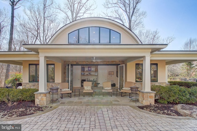 back of property featuring stone siding, a patio, and stucco siding