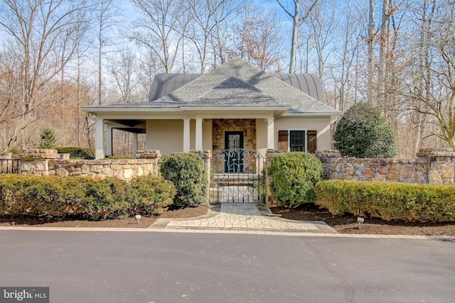 view of front of property featuring stone siding, roof with shingles, a gate, and stucco siding