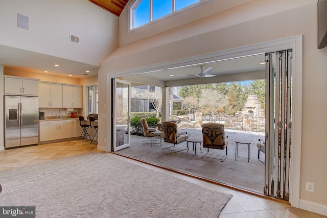 doorway with recessed lighting, visible vents, a high ceiling, a ceiling fan, and baseboards