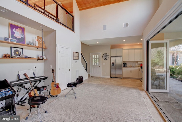 interior space with baseboards, visible vents, a towering ceiling, stairs, and recessed lighting