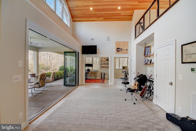 entryway with wood ceiling, a high ceiling, visible vents, and baseboards