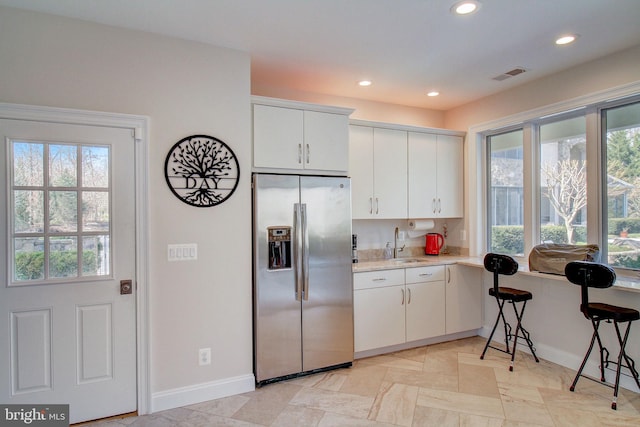 kitchen featuring recessed lighting, a sink, visible vents, light countertops, and stainless steel fridge with ice dispenser