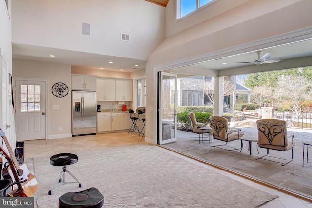 interior space with recessed lighting, a ceiling fan, baseboards, a towering ceiling, and visible vents