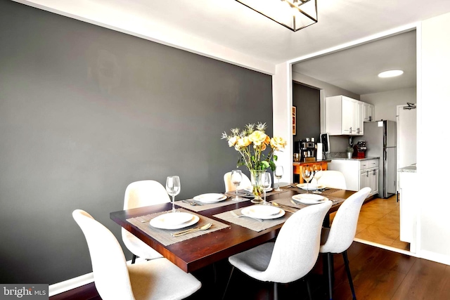 dining space with baseboards and wood finished floors