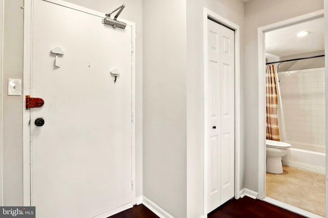 full bath with shower / bathtub combination with curtain, a closet, toilet, and baseboards