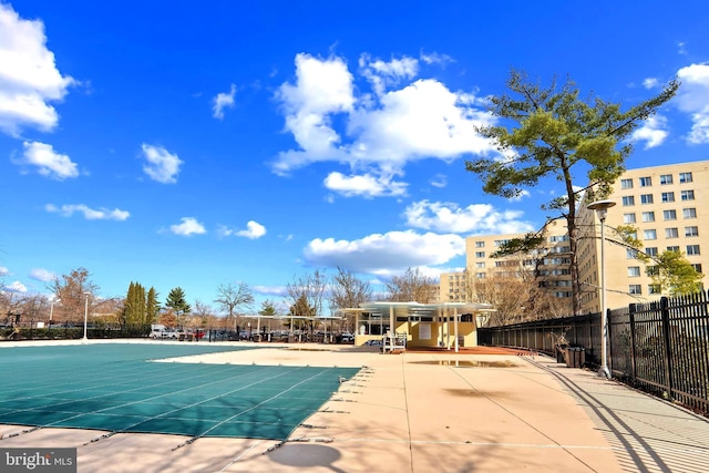 community pool with a patio area and fence