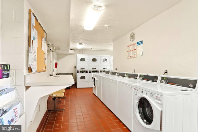 common laundry area with a textured ceiling, tile patterned flooring, concrete block wall, washing machine and clothes dryer, and stacked washer and clothes dryer