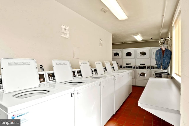 shared laundry area with washing machine and dryer, stacked washer / dryer, and dark tile patterned flooring