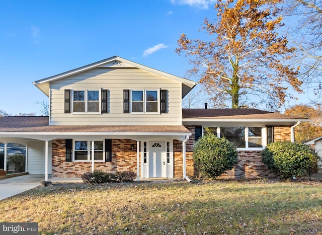 split level home with an attached carport, brick siding, driveway, and a front yard